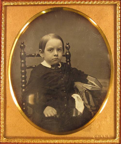 Young boy seated at a table with open book in hand