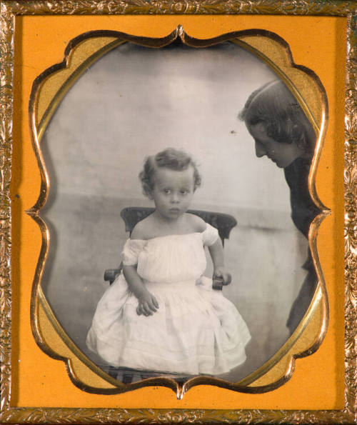 Mother leaning into frame toward seated child