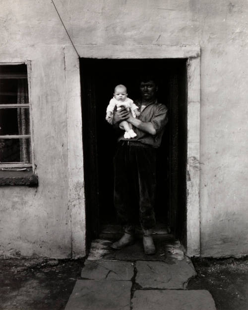 Miner holding baby in doorway