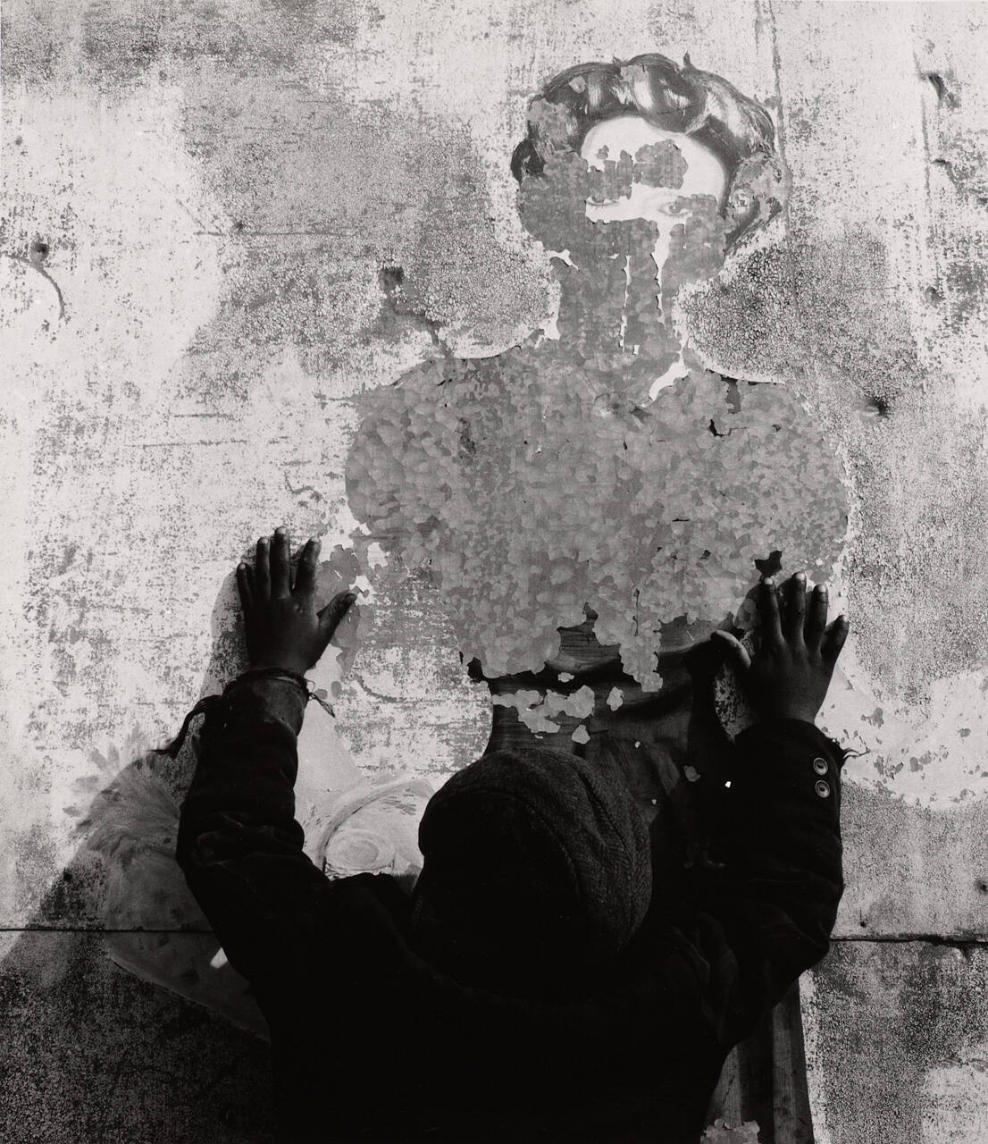 [Black child reaching for image of woman in chipped paint]