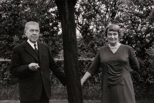 Rene and Georgette Magritte holding hands behind a tree
