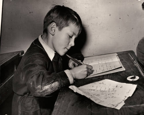 Untitled (Boy writing on school desk)