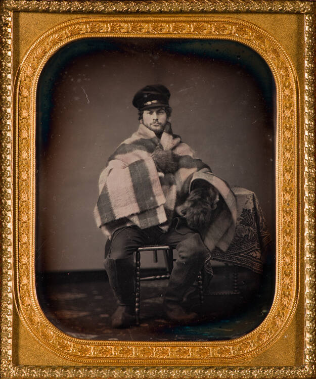 Man wearing fur gloves and wrapped in blanket