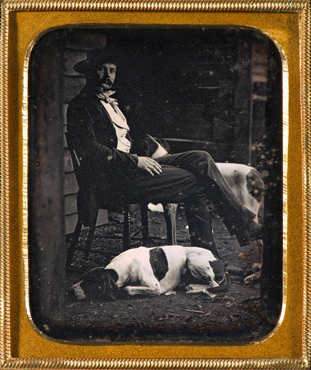 Man on front porch with two hunting dogs