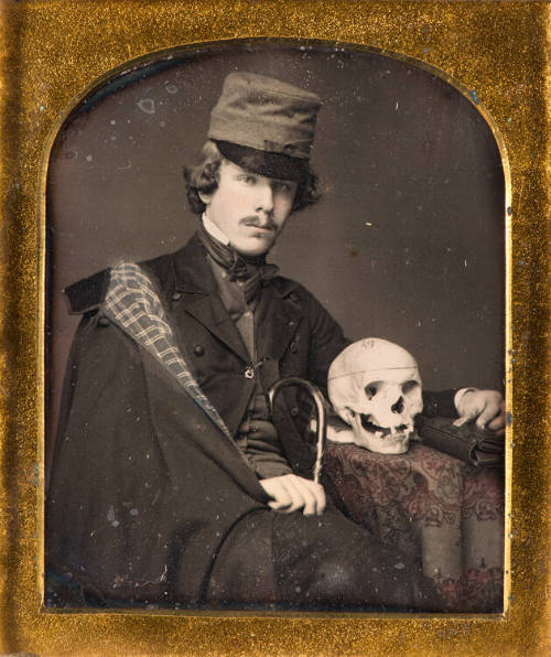Man seated at table with skull