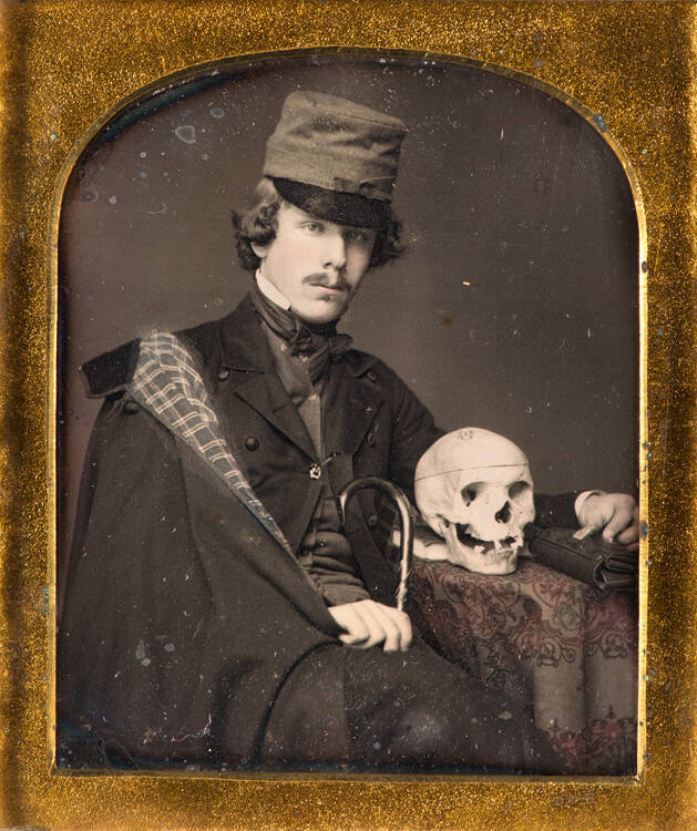 Man seated at table with skull