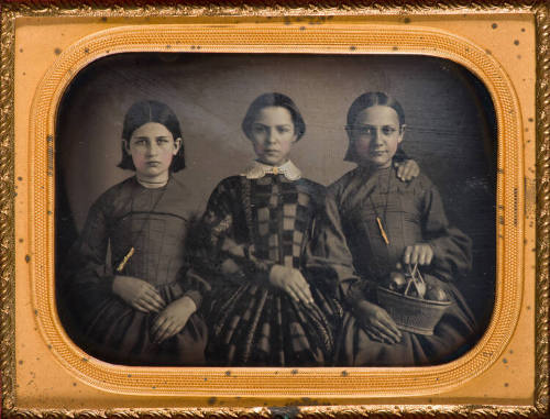 Mother and daughters, one holding basket of apples