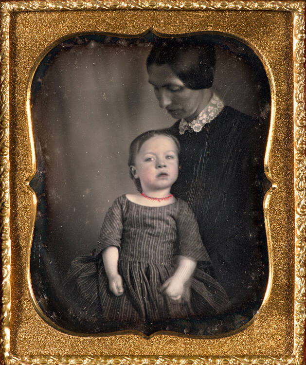 Mother holding young child (looking down toward child)