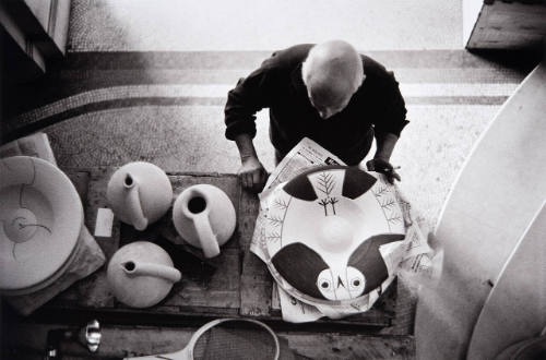 Picasso examines other, newly painted platters before they go to the kiln--fish and bird designs