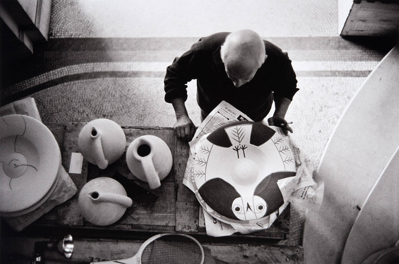 Picasso examines other, newly painted platters before they go to the kiln--fish and bird designs