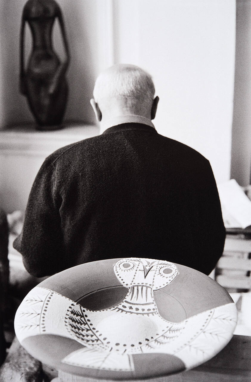 Picasso examines other, newly painted platters before they go to the kiln--fish and bird designs