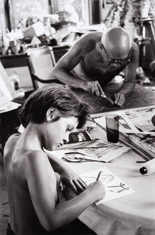 Paloma with her father at dinner table. Paloma draws while Picasso works.