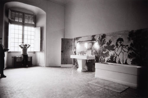 Jacqueline arranging her hair in the morning sunlight while seated on a newly installed radiator in the bathroom of the château