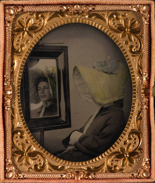 Woman in bonnet looking in mirror