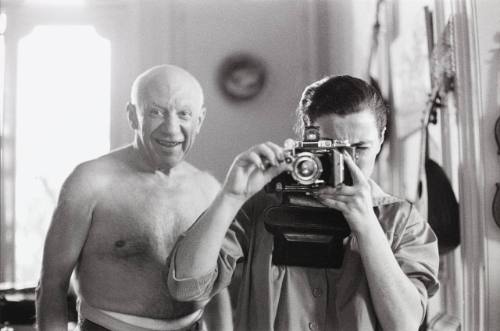A smiling Picasso looks over Jacqueline's shoulder as she aims her camera at the photographer, Villa La Californie