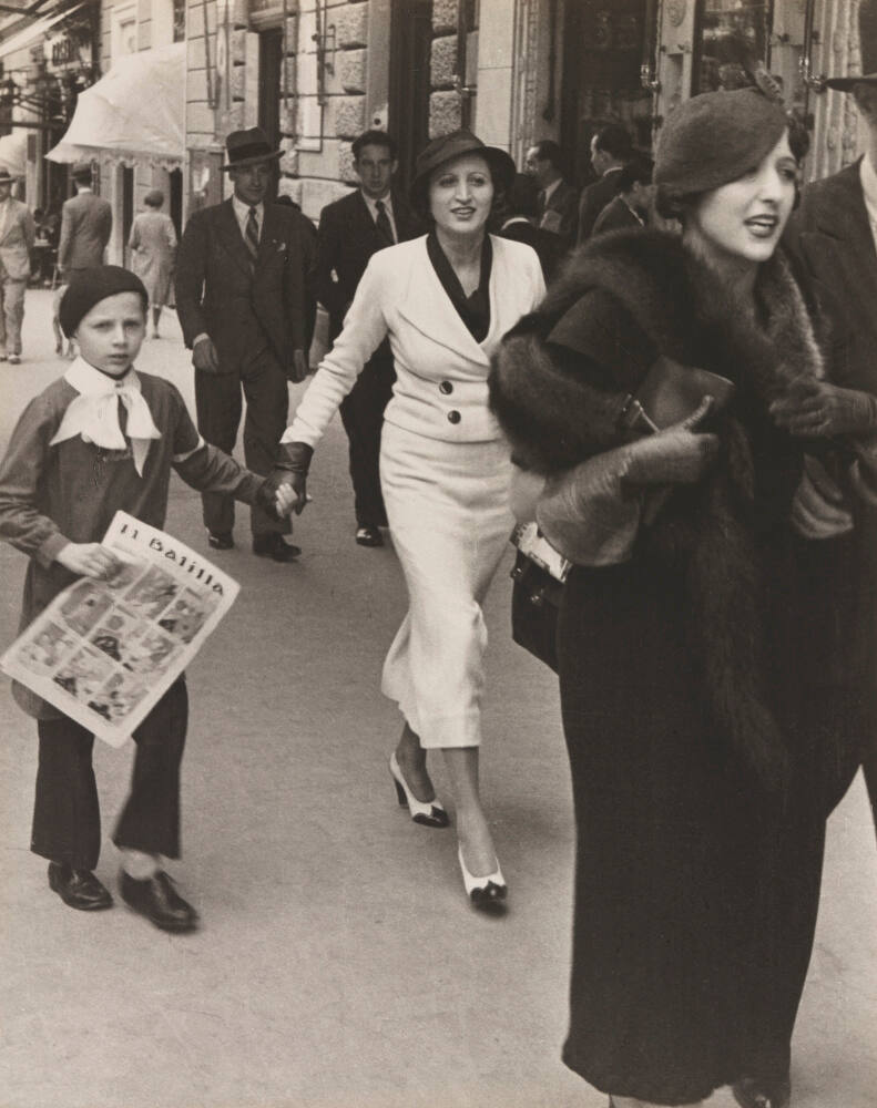 Fashionable Via Veneto [street] in Rome. Youngster carrying paper belongs to Il Balilla, Facist youth organization